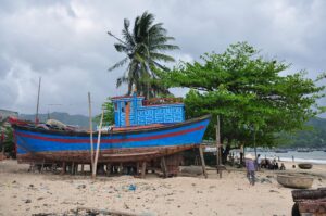 A vibrant fishing boat stands on a sunny beach in Khánh Hòa, Vietnam, offering a scenic coastal view.