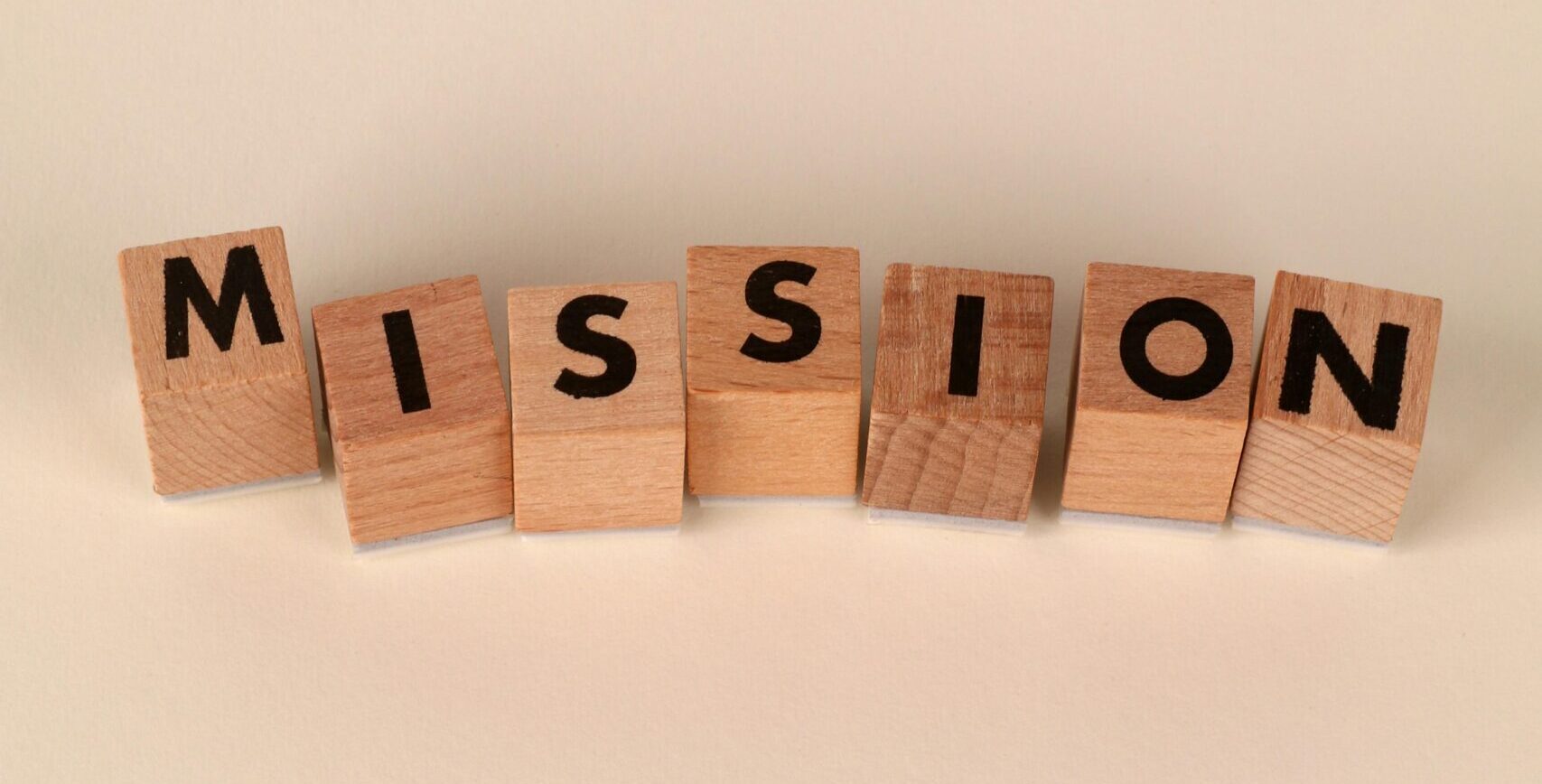 Home Wooden blocks with letters spelling 'Mission' on a soft neutral background, ideal for business themes.